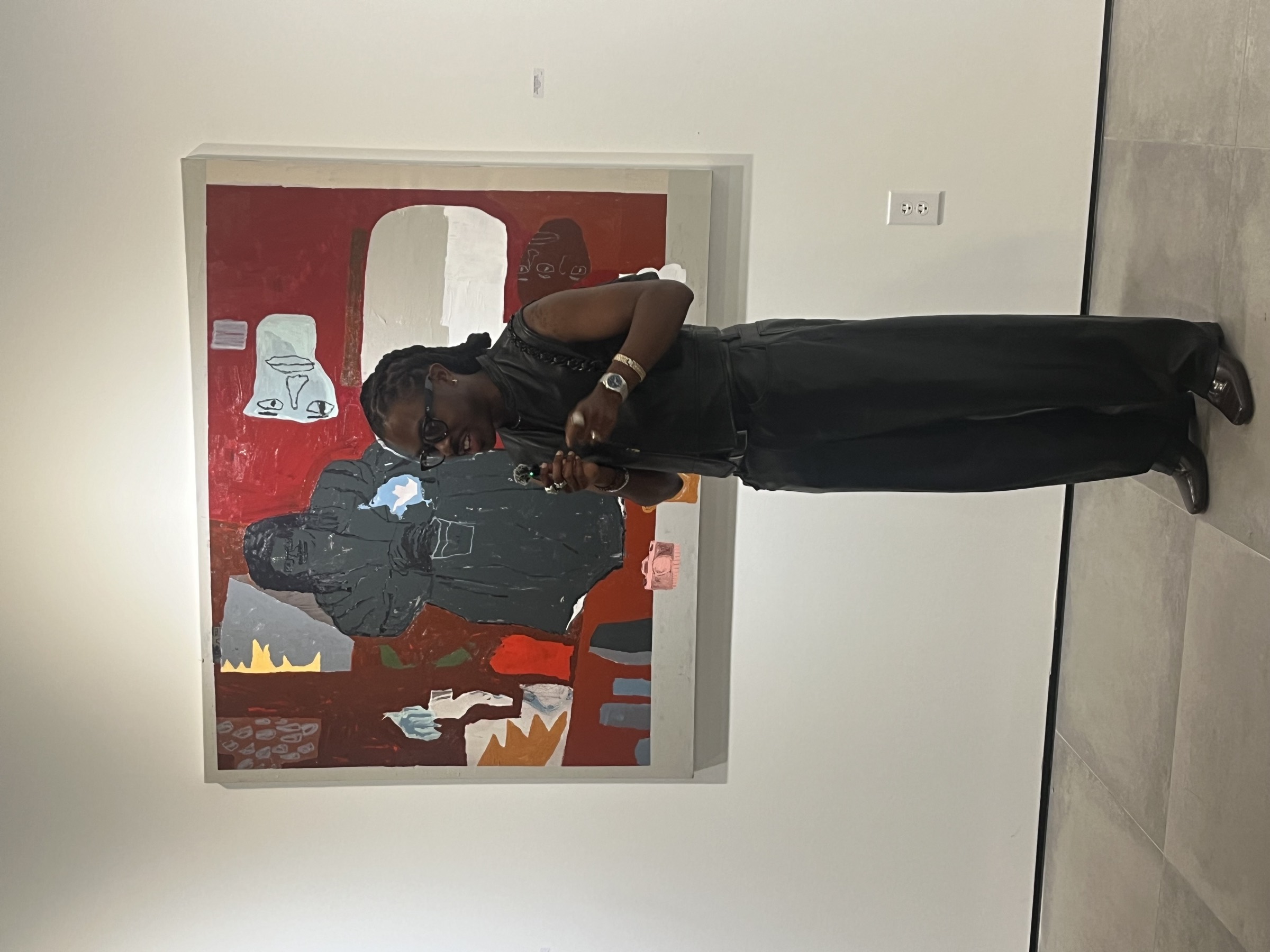 Bhare speaking into a microphone in front of a red painting at a gallery